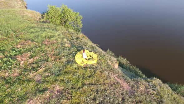 A Girl with Loose Hair in a Dress Stands on the High Bank of the Lake