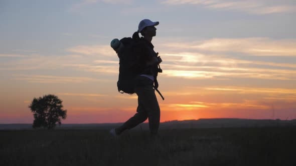 Woman Traveler with Backpack Hiking in Mountains. Silhouette Hiker Walking in the Mountains, Freedom