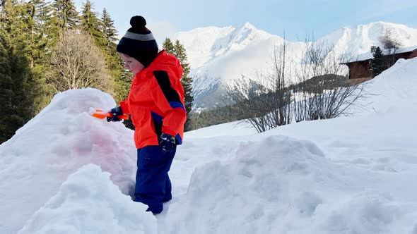 Happy Toddler Boy Play with Shovel in Snow at Winter Vacations