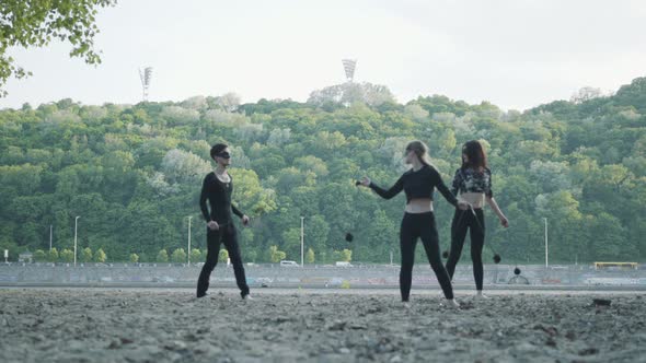 Young Slim Man and Two Beautiful Women Simultaneously Perform Show with Flame While Standing