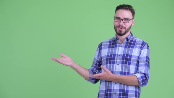 Happy Young Bearded Hipster Man Talking While Showing Something