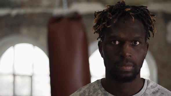 African American Boxer with Boxing Pear on Background Looking to the Camera