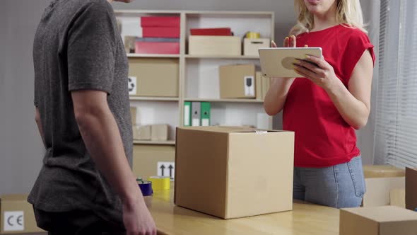 Female Warehouse Worker Online Store Owner Gives the Man to the Courier a Cardboard Box of the