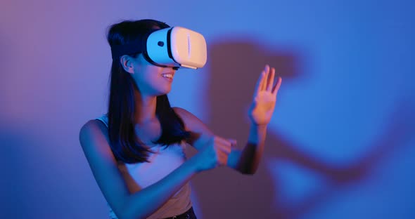 Woman playing with VR headset with cyber lighting