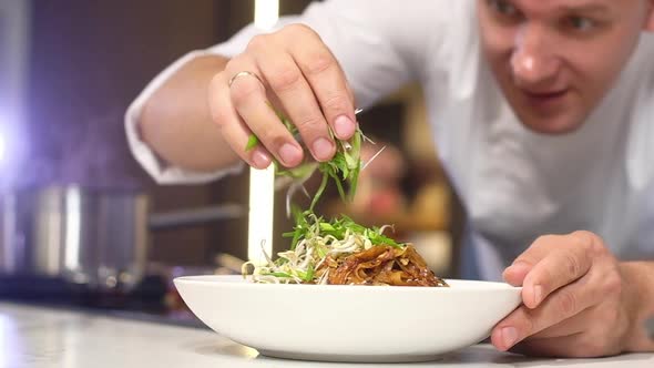 Young professional chef in the kitchen prepares Italian pasta decorates dish