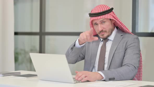 Middle Aged Arab Businessman Pointing at Camera while using Laptop in Office