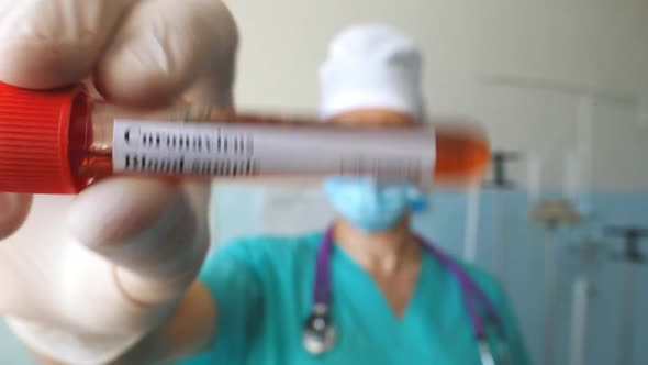 Hand of Doctor Holding Test Tube with Blood Sample To Coronavirus. Arm of Medic with Protective