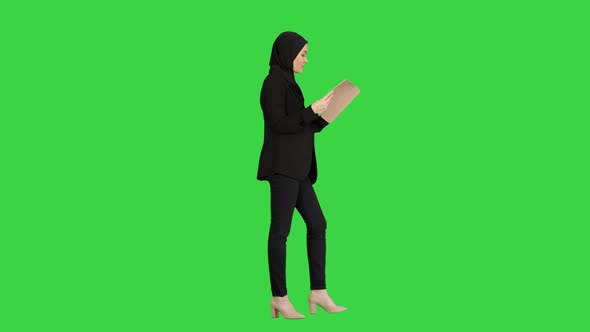 Surprised Muslim Businesswoman Reading Business Diary and Shaking Her Head While Walking on a Green