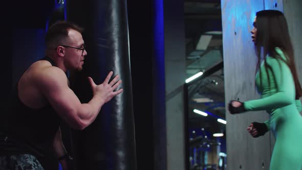 Woman Having a Boxing Training with a Coach  Hitting the Punching Bag