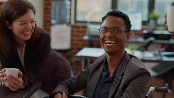 Young Man in Wheelchair Having Fun at Work with Colleagues