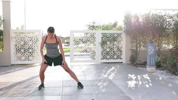 Young woman doing stretching exercise outdoors on a sunny morning