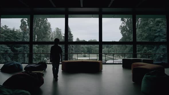 Silhouette Lonely Little Boy Walking in Dark School Hall with Panoramic Window