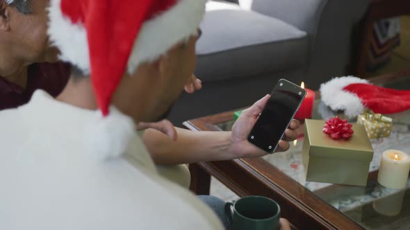 Son and father making christmas video call on smartphone with blank screen and copy space at home