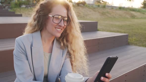 Smiling Woman Scrolling on Smartphone Outdoors