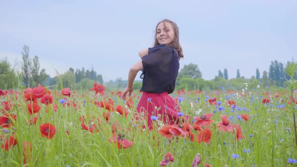 Pretty Young Woman Running and Dancing in a Poppy Field Smiling Happily. Connection with Nature