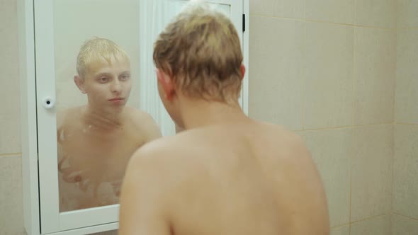 Handsome Man Looking Face In Front Of Mirror. Sexy Manat Bathroom.