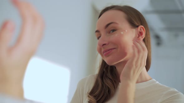 Young Woman Applying Cream on Her Face