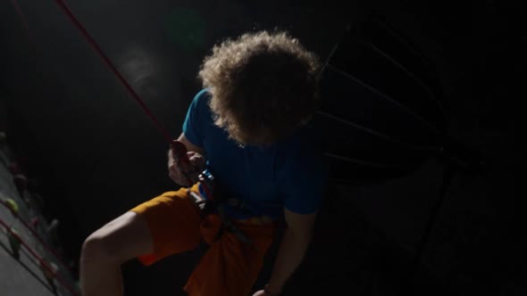 Young Man Professional Climber Training on a Climbing Wall Practicing Rockclimbing and Descends From