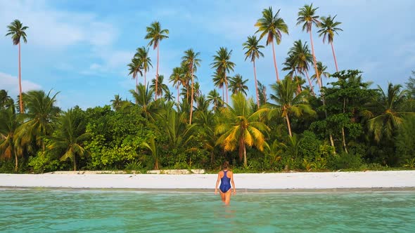 Slow motion: woman walking on white sand beach turquoise water tropical coastlin