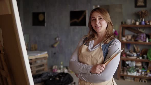 Portrait Shot of the Charming and Pretty Caucasian Woman Artist Standing Crossed Arm in the Studio