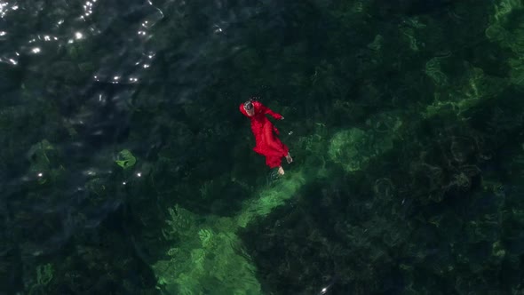 Woman in a Red Long Dress Is Lying on Her Back Bathing in the Green