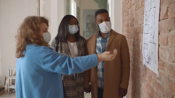 Lovely Black Family and Professional Designer in Protective Mask Discussing Concept of Future