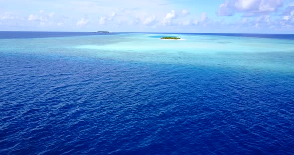 Tropical flying travel shot of a sandy white paradise beach and blue sea background in hi res 4K