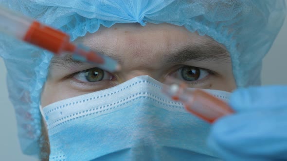 Male doctor holding syringe with blood sample of coronavirus infection. Coronavirus concept