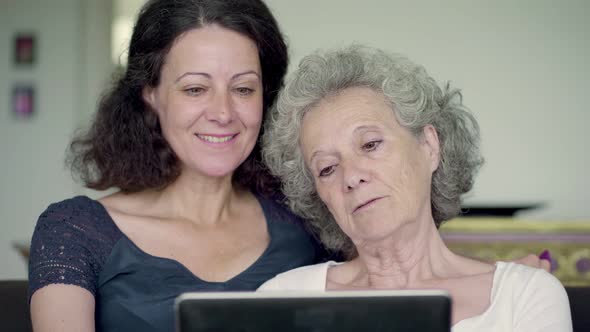Daughter and Mother Holding Tablet, Googling and Swiping Photos