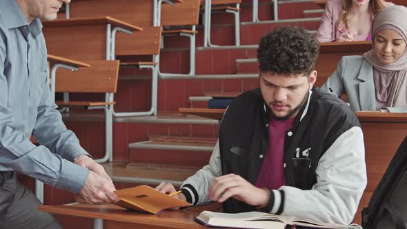 University Professor Helping Male Student during Test