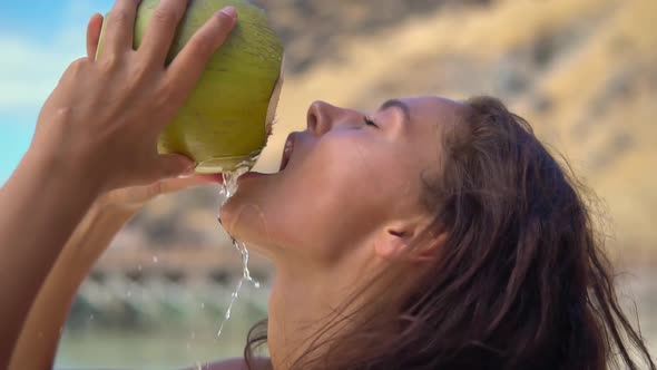 Young Woman Drinks Fresh Coconut Juice Holding Up Her Head While Standing on Sunny Tropical Beach