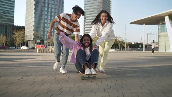 Teenage Multiracial Asian and Latin Friends Have Fun Together on Skateboard in a Modern City