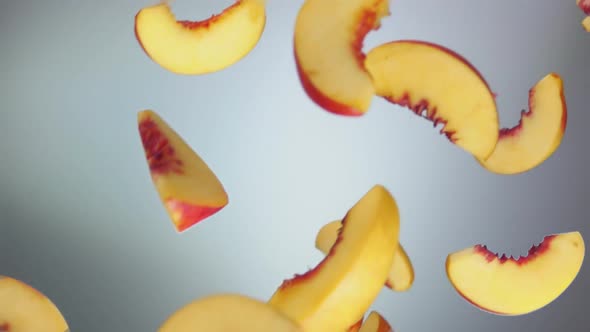 Closeup of the Juicy Peach Slices Falling and Spinning on the White Background