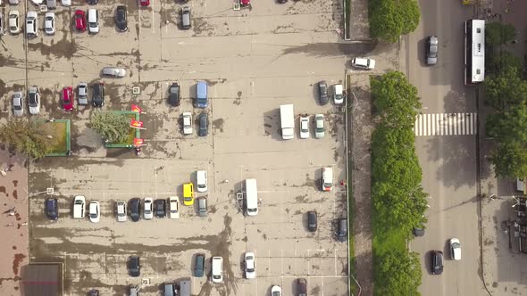 Aerial top down view of parking lot with parked vehicles and street with moving cars and zebra