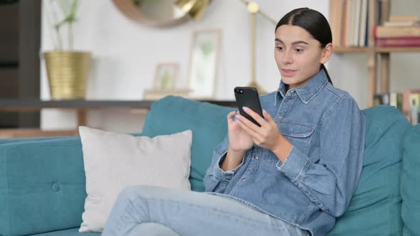 Latin Woman Cheering on Smartphone at Work Success