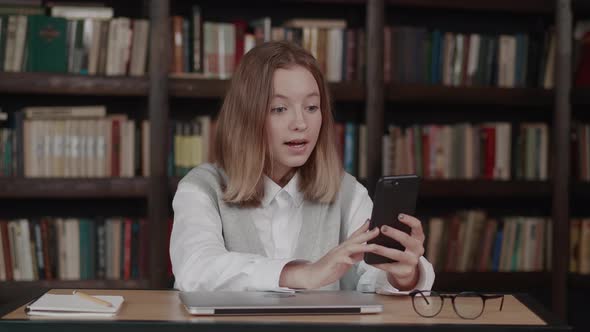 Smart Teen Girl School Pupil Waving Hand Using Video Conference Call By Webcam on Smartphone Library