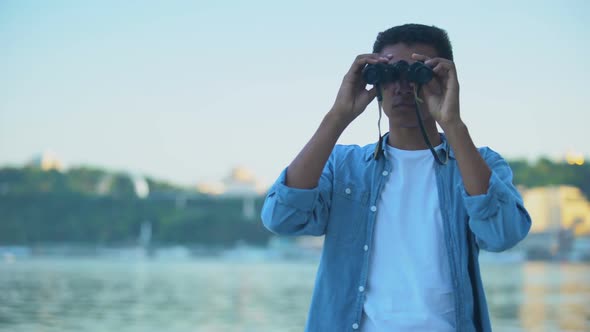 Curious Teenager Spending Time on River Embankment, Looking Through Binoculars