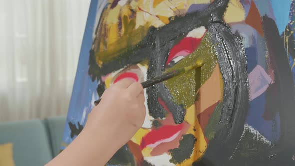 Close Up Of A Hand's Girl Holding Paintbrush And Painting A Girl's Face On The Canvas