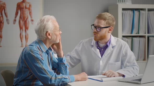 Young Doctor Encouraging Senior Patient in Office