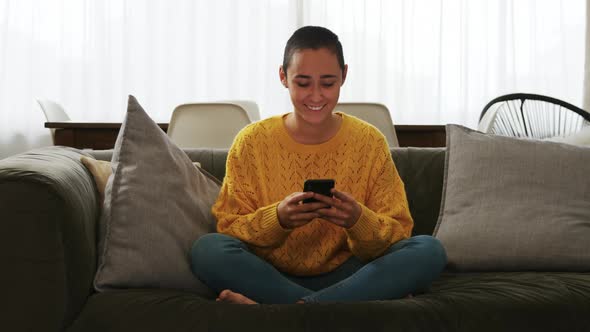 Woman using smartphone and smiling in living room