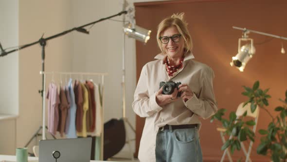 Senior Female Photographer Holding Camera and Smiling