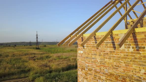 Aerial View of Unfinished Brick House with Wooden Roof Structure Under Construction