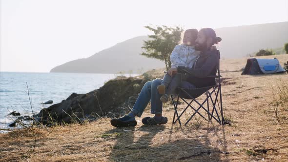 Little Child Girl Comes To Her Father and His Puts Her in His Knees Outdoor