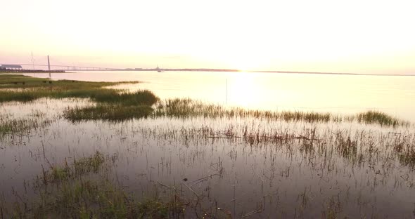 Flying over marsh grass at sunrise with boat