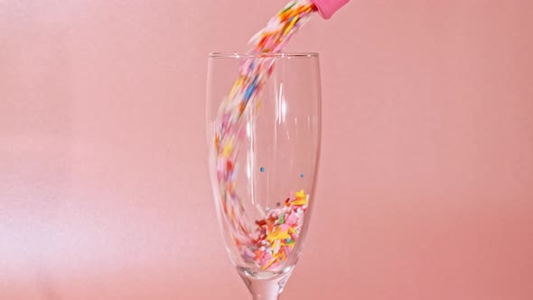 Colorful Candy Confectionery Run Poured Into a Wineglass Glass on Pink Background