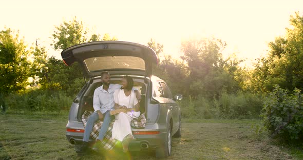 Lovely Black Couple Sitting in a Car Trunk