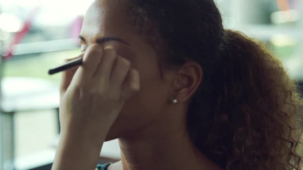 Makeup artist applying eye shadow on womens eyes