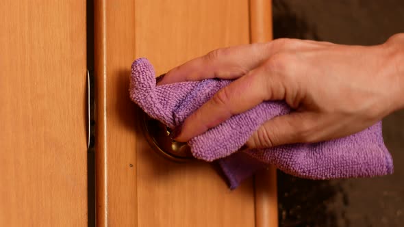 A woman is wiping off dirt and bacteria from the door handle with a rag