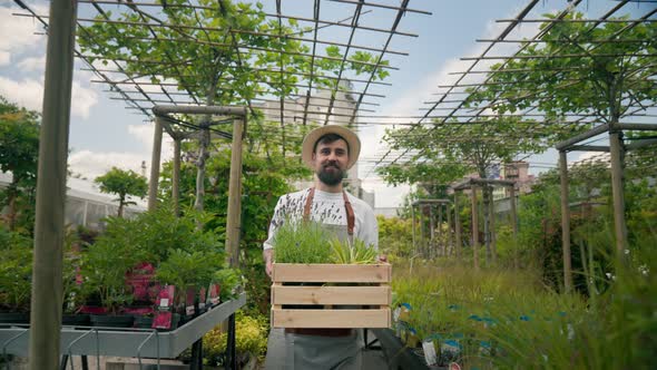 Portrait of Goodlooking Men Gardener Holding Wooden Box with Pots with Decorative Flowers