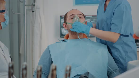 Patient with Oxygen Mask Receiving Anesthesic in Dentistry Cabinet